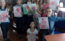 uśmiechnięte dzieci w wieku przedszkolnym przedstawiają swoje prace